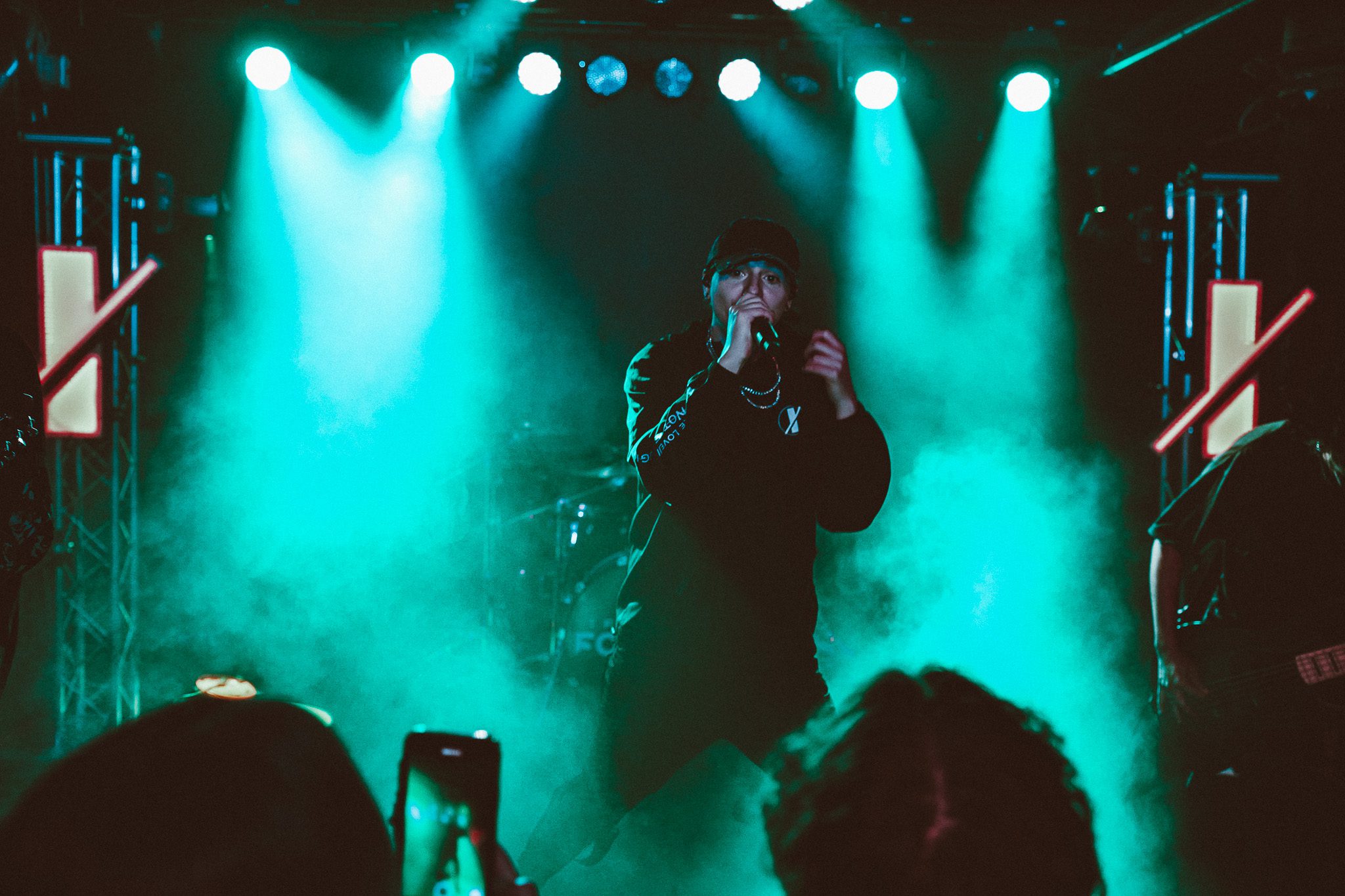 A vocalist passionately performing on stage, holding a microphone and delivering an intense performance, with dynamic lighting in the background.