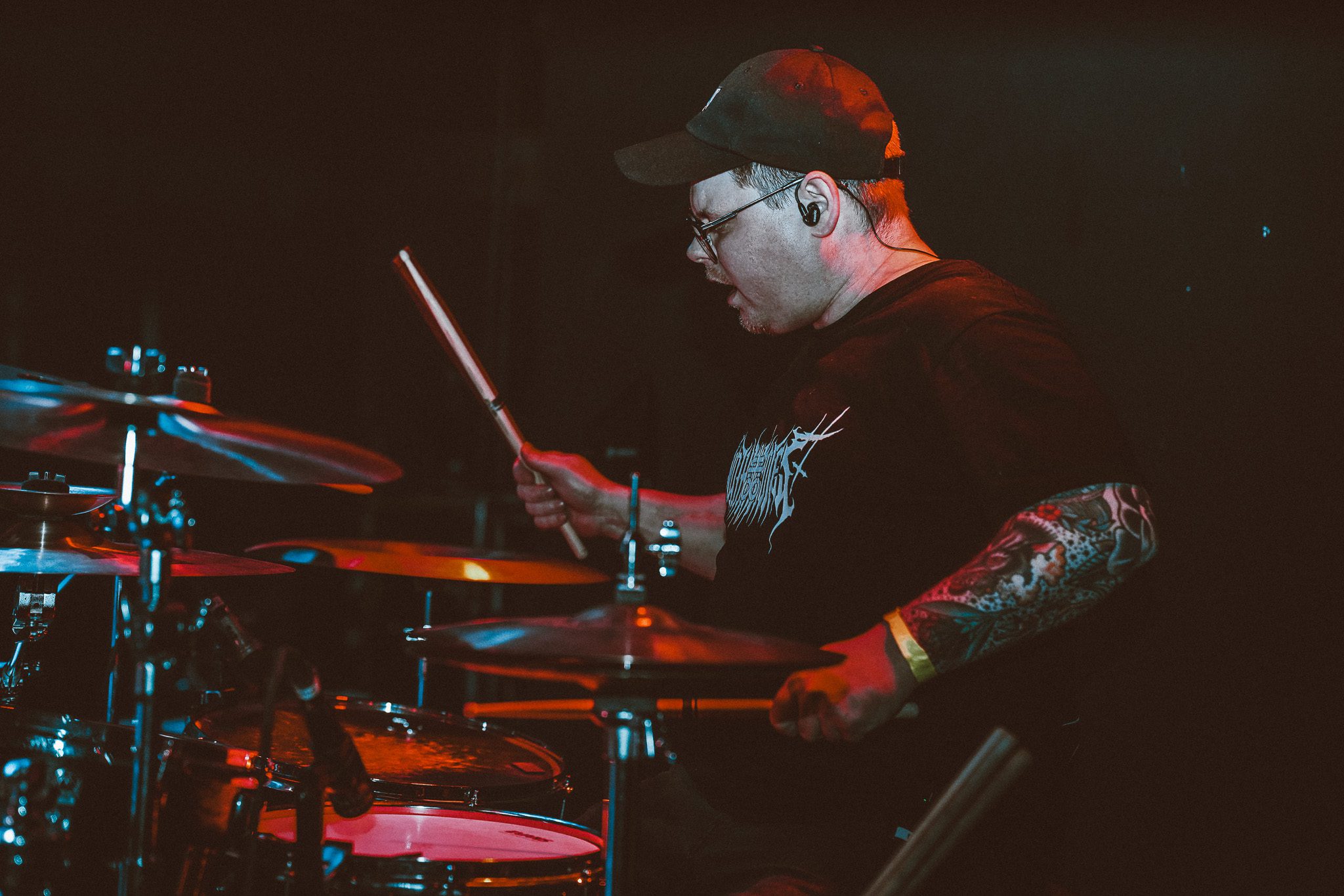 A metal band performing on stage with dynamic lighting, featuring a vocalist in a plaid shirt and musicians playing guitar and bass.