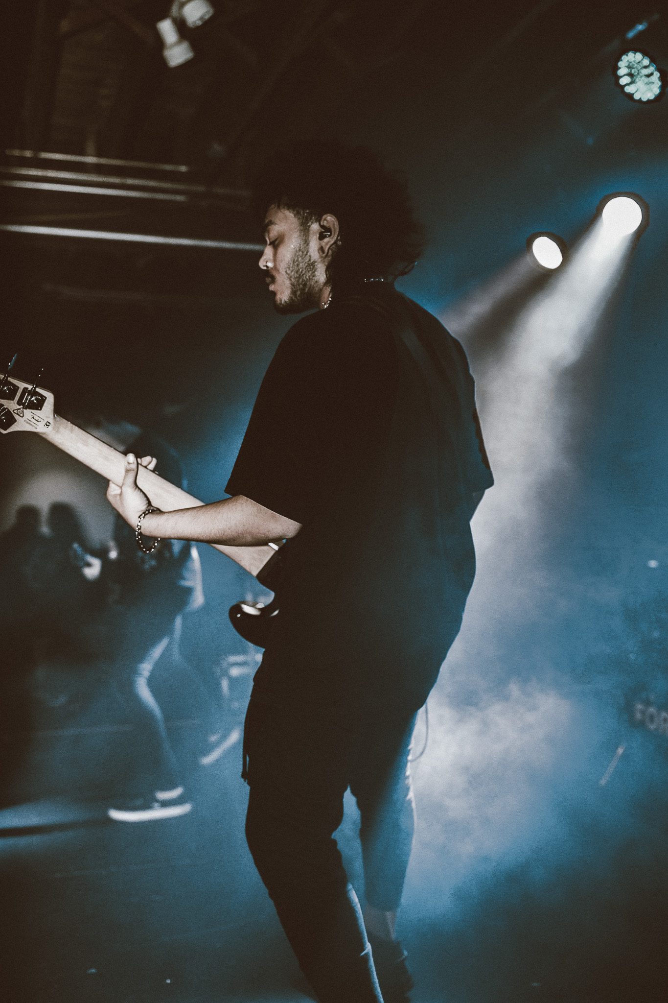 A tattooed male performer on stage, passionately engaging with the audience while wearing a black shirt and showcasing a dynamic posture.