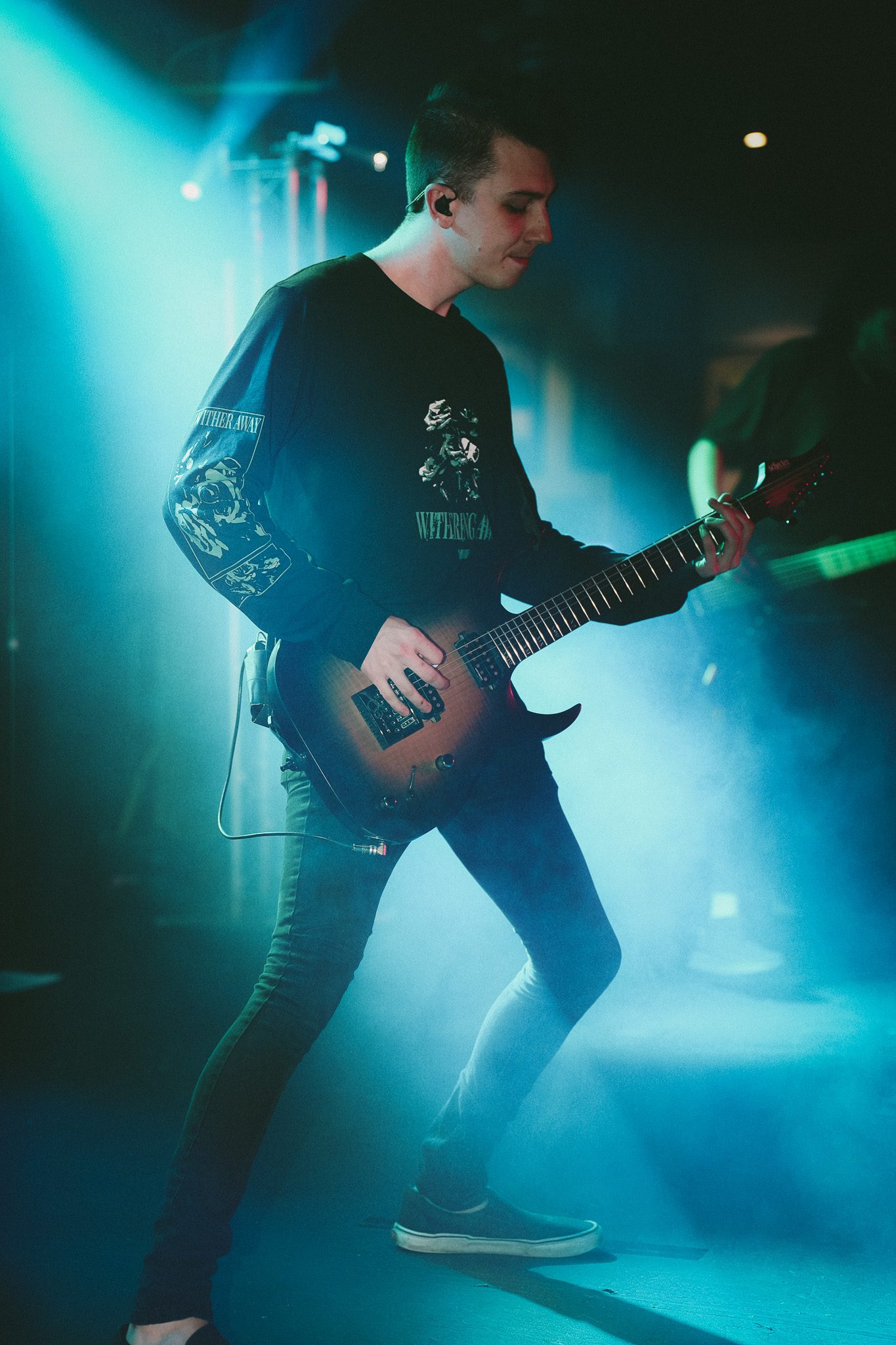 Two musicians performing on stage during a live concert, with dramatic lighting and an energetic atmosphere.