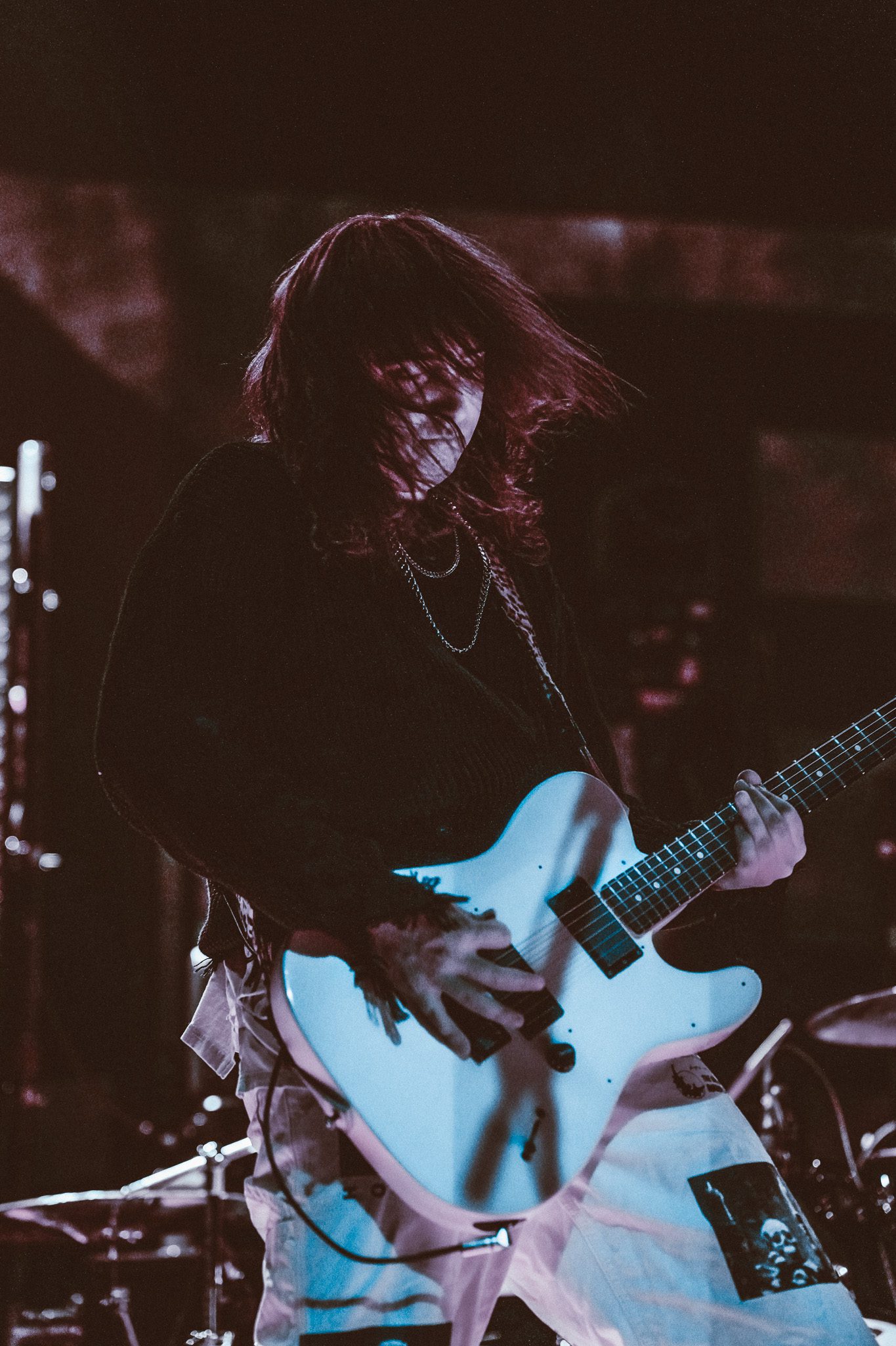 A musician playing an electric guitar on stage, captured from a low angle, with bright stage lights in the background.