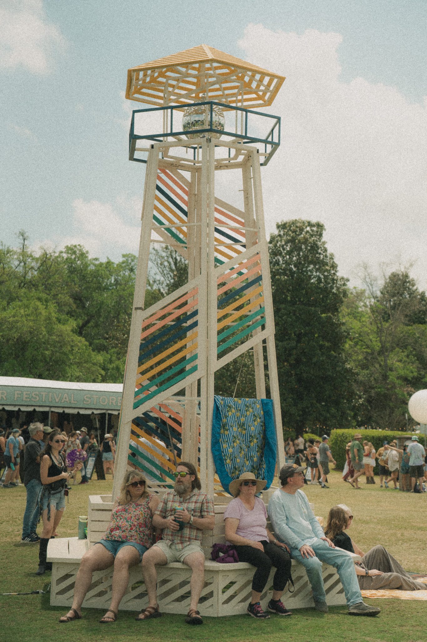 A colorful lookout tower with artistic patterns, surrounded by festival attendees enjoying the atmosphere.
