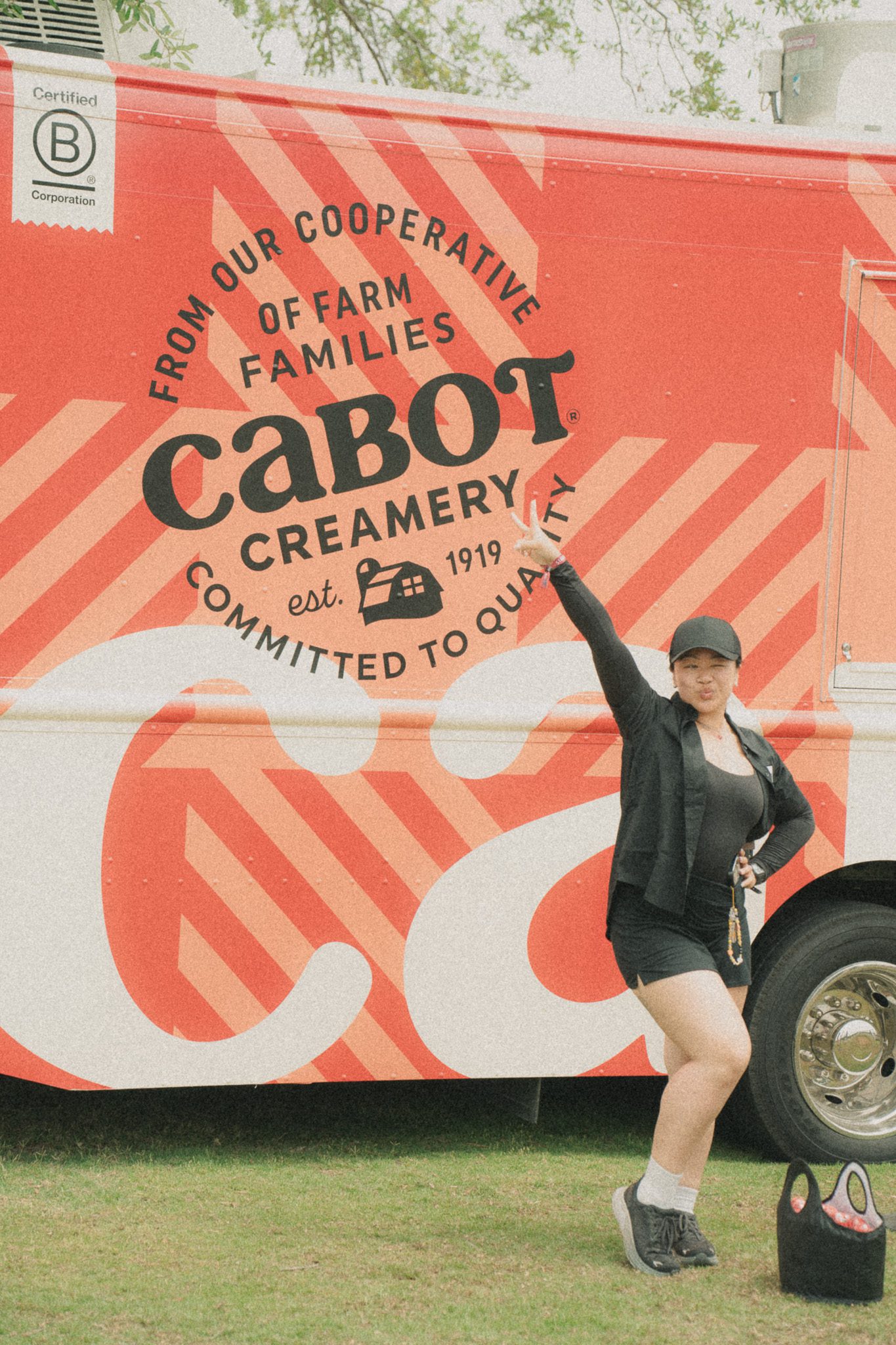 A person poses in front of a vibrant food truck featuring the Cabot Creamery logo, raising one arm in excitement.