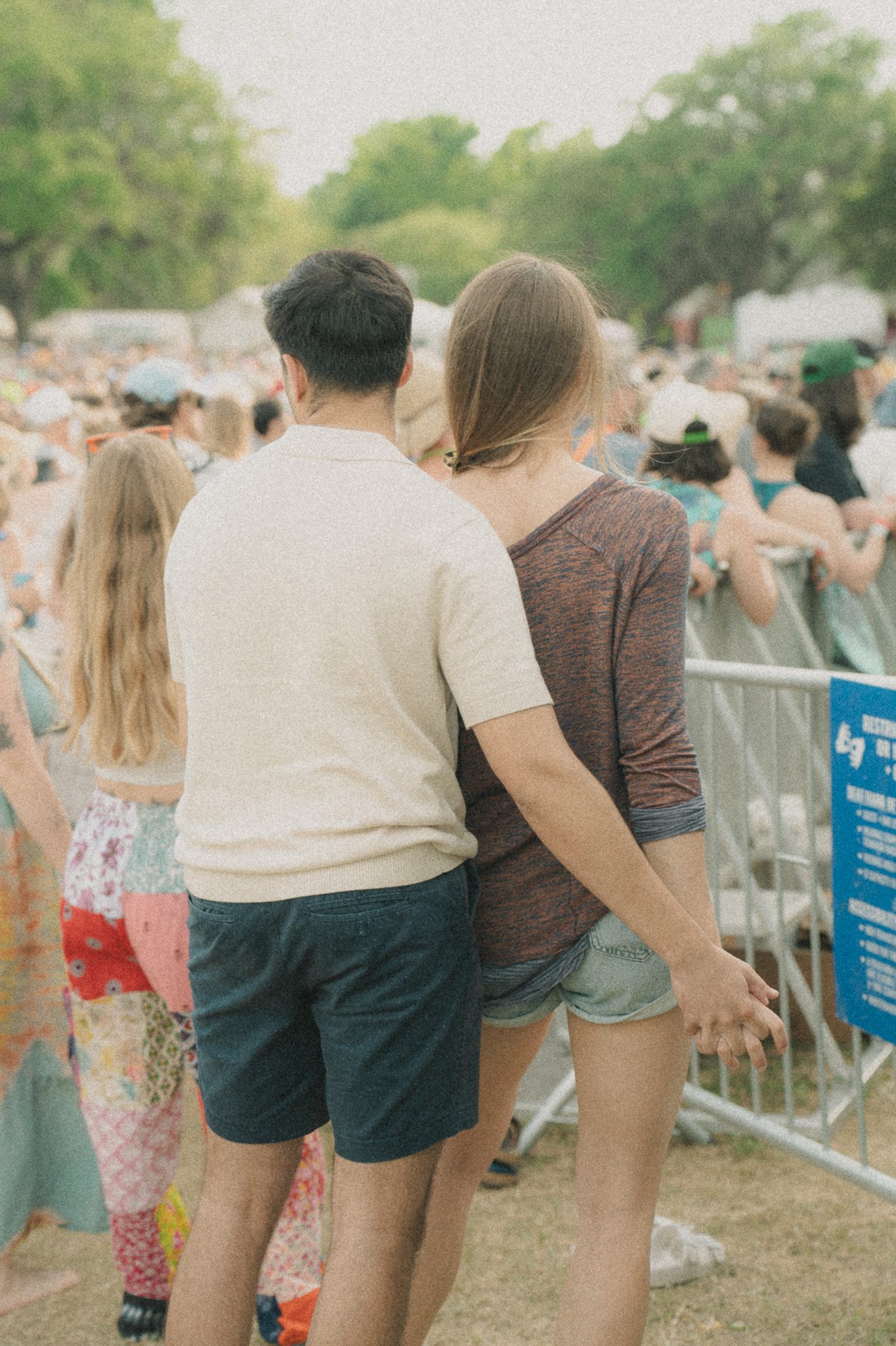 A couple at a festival standing close together, holding hands while enjoying the atmosphere.