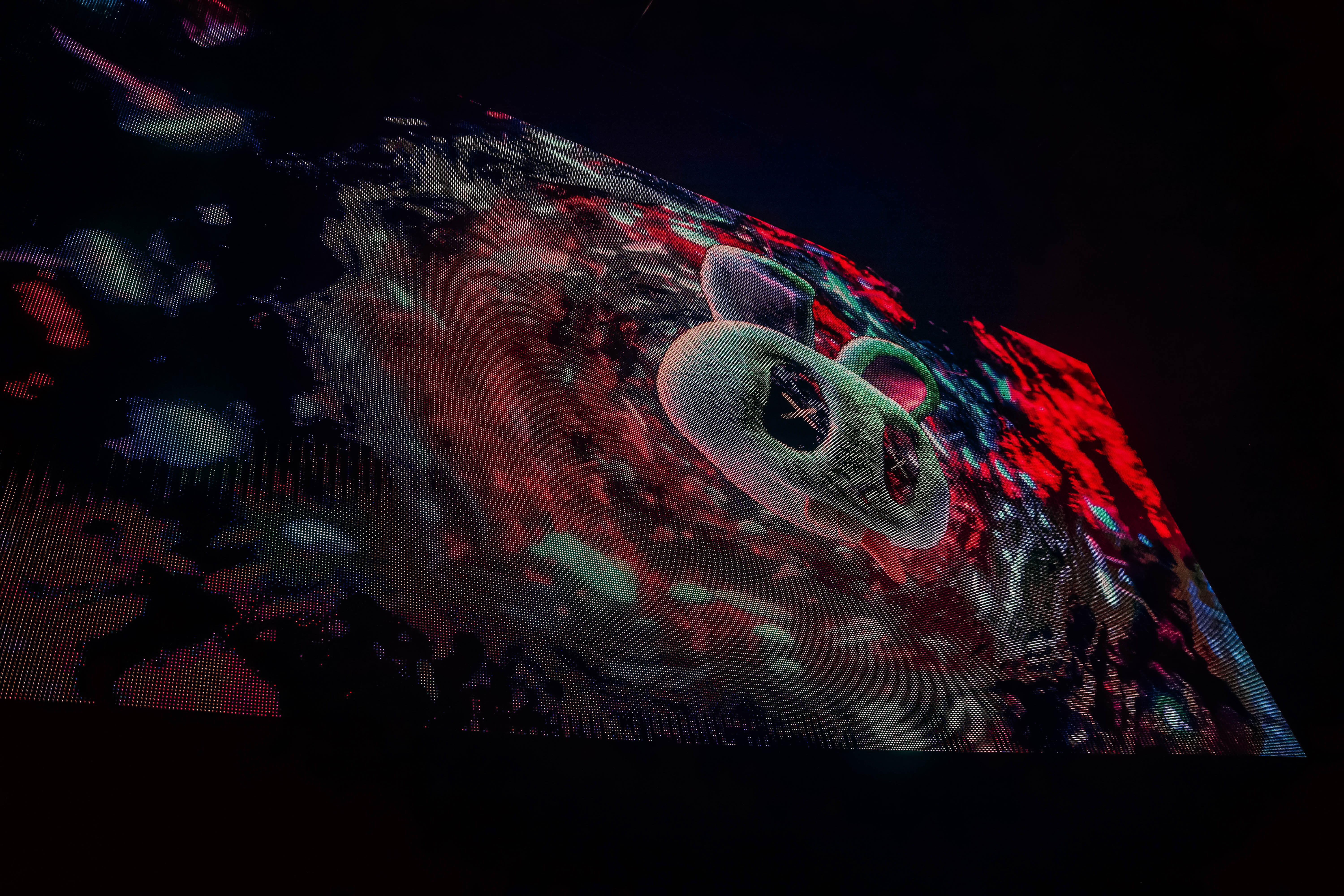 A colorful animated visual featuring a stylized bear character against a vibrant, abstract background, showcasing the artistic atmosphere of a live music event.