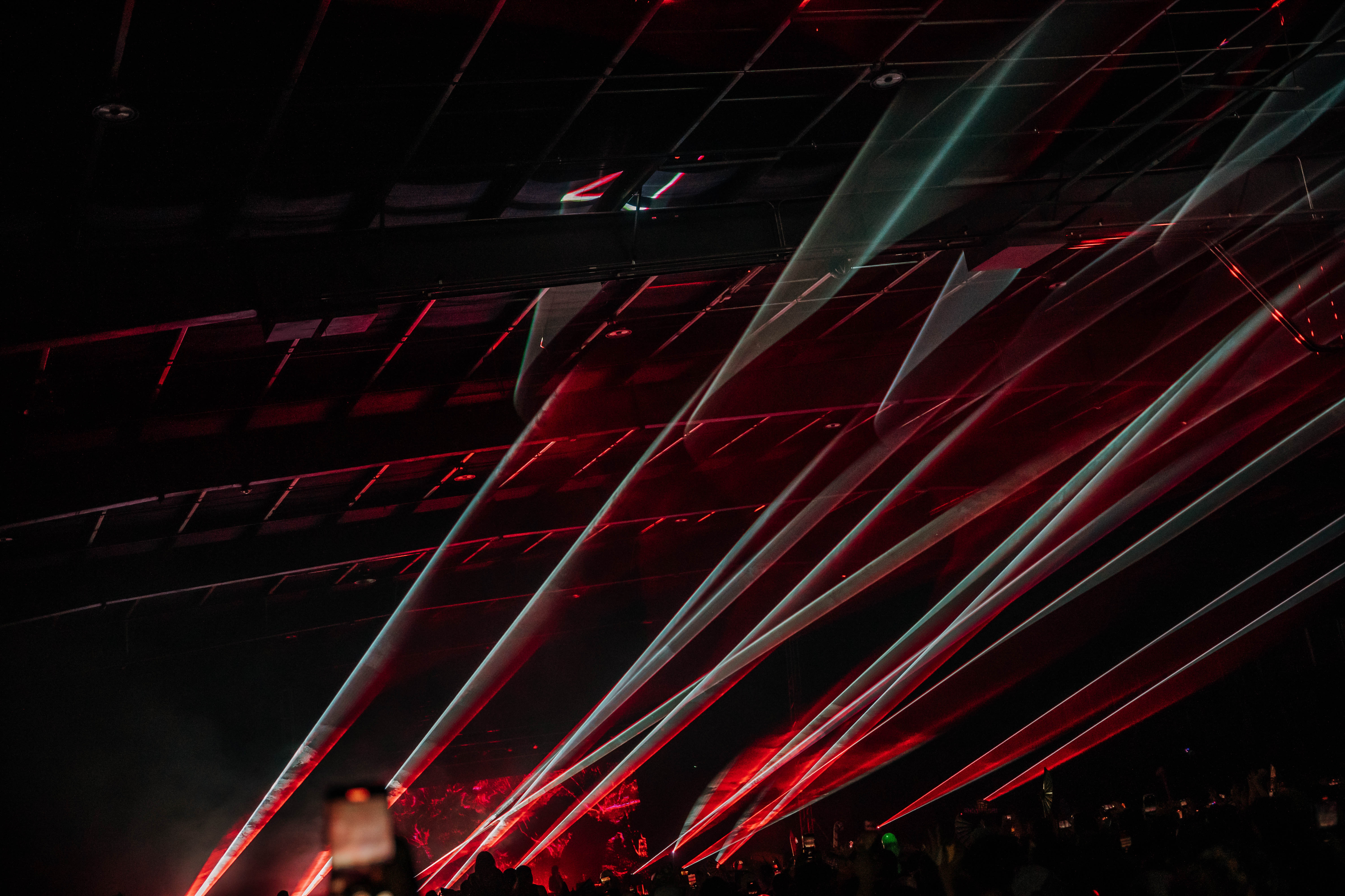 Dynamic laser light show at a concert, with beams of red and green lights cutting through a dark venue, capturing the electrifying atmosphere.