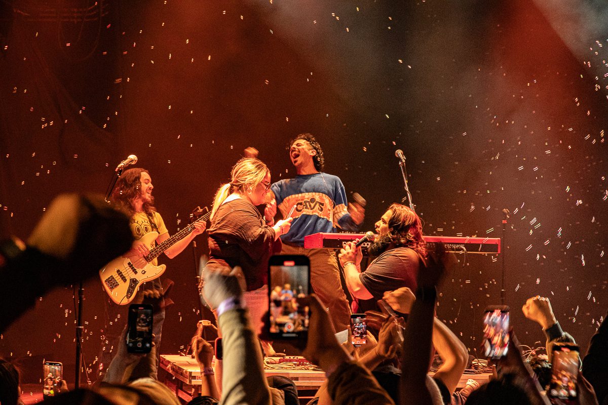 Anees performs energetically on stage at the House of Blues in Cleveland, surrounded by excited fans and band members, with confetti falling in the background.
