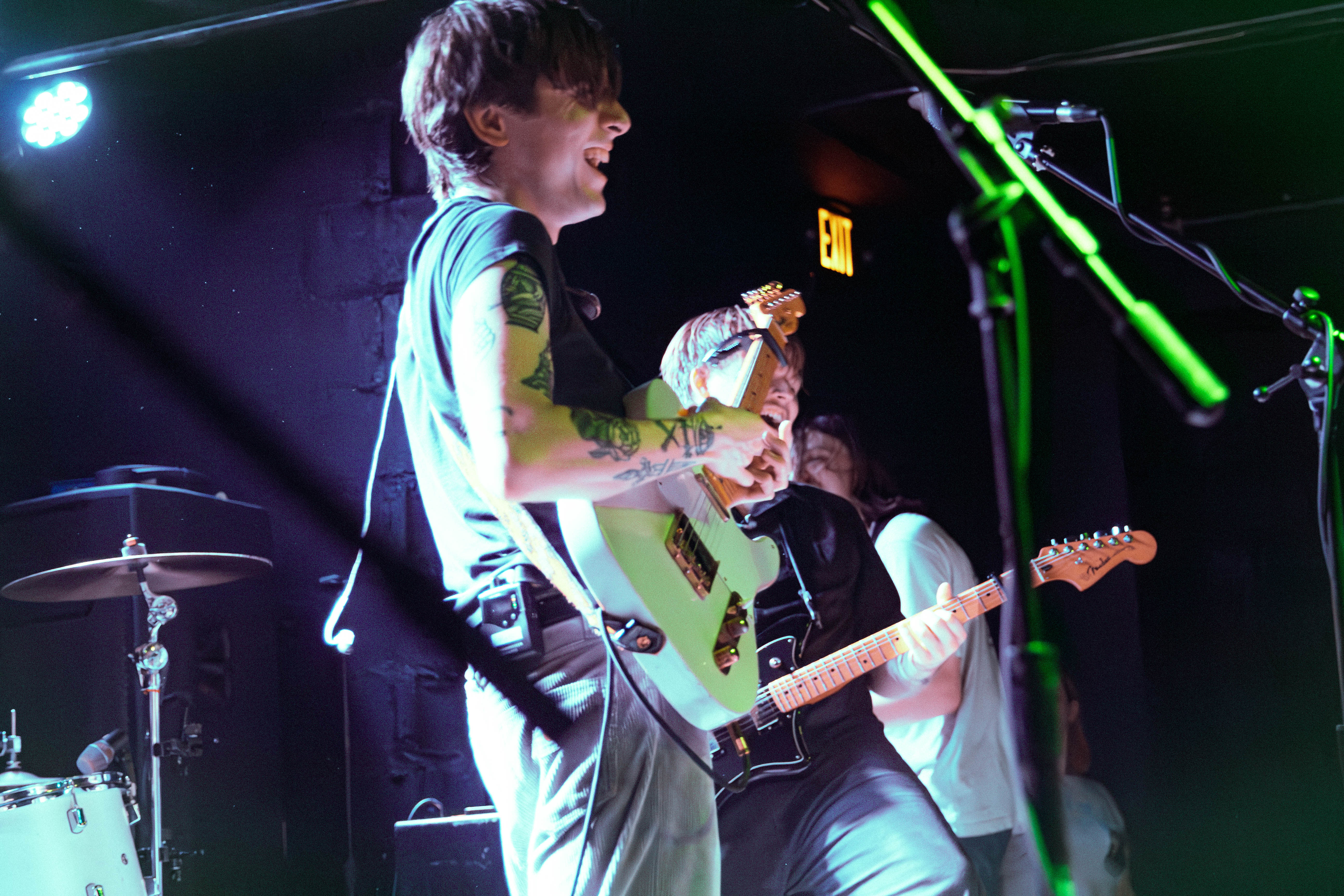 A live performance by the band Arm's Length, showcasing band members playing electric guitars and enjoying the moment on stage.