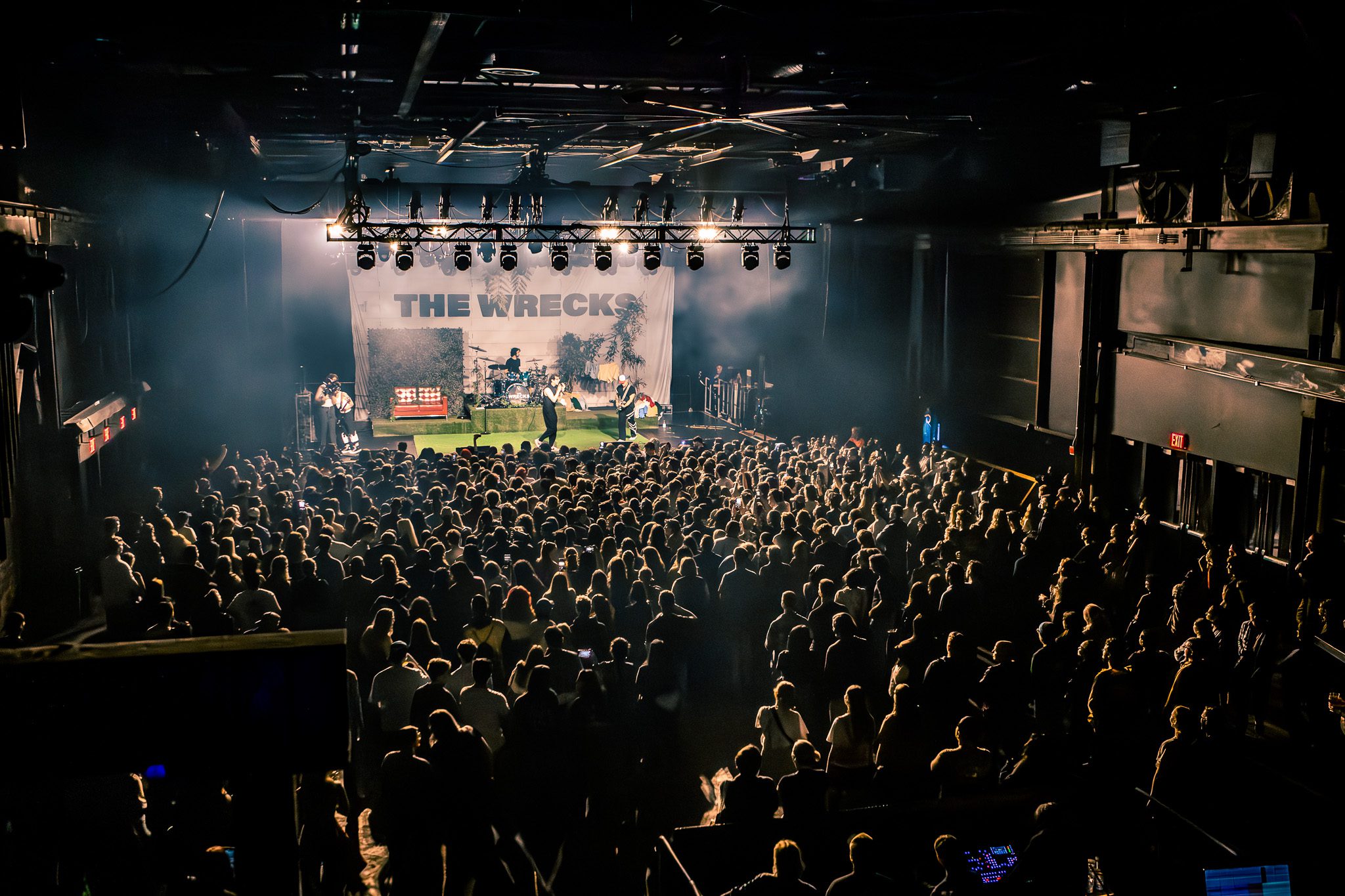 A crowd gathered at Brooklyn Steel for a performance by The Wrecks, featuring a stage with vibrant lighting and a backdrop displaying the band's name.