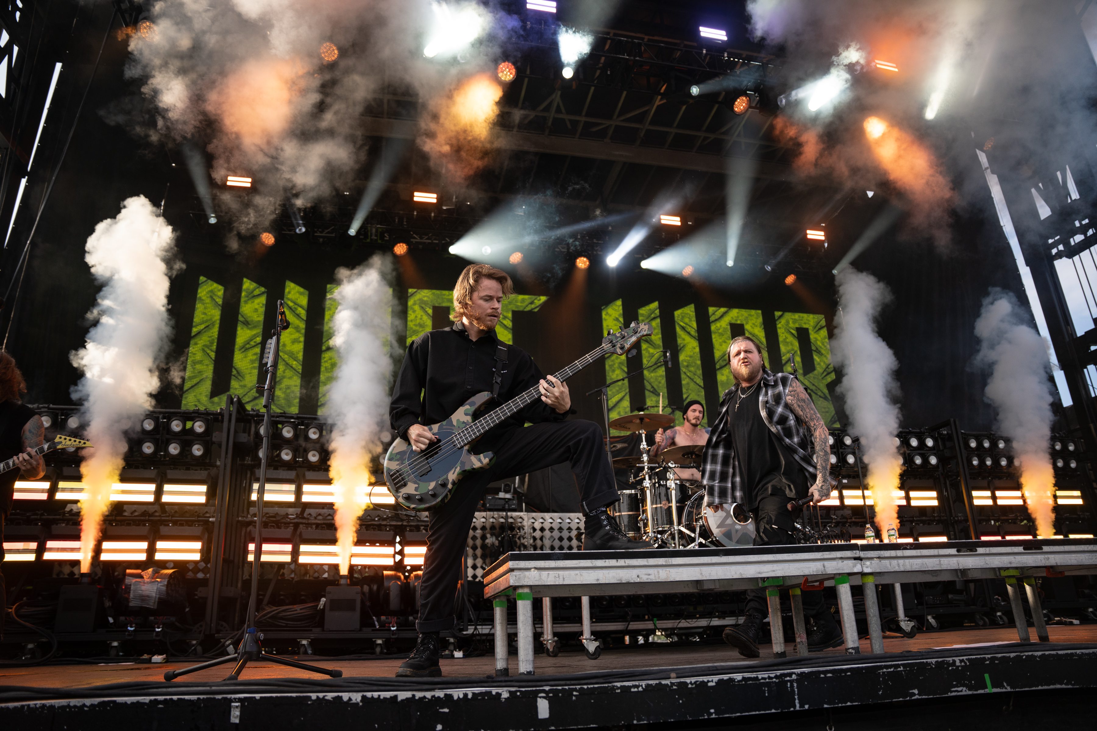 A live performance by the band Wage War on stage, showcasing a dynamic atmosphere with smoke effects and vibrant lighting.
