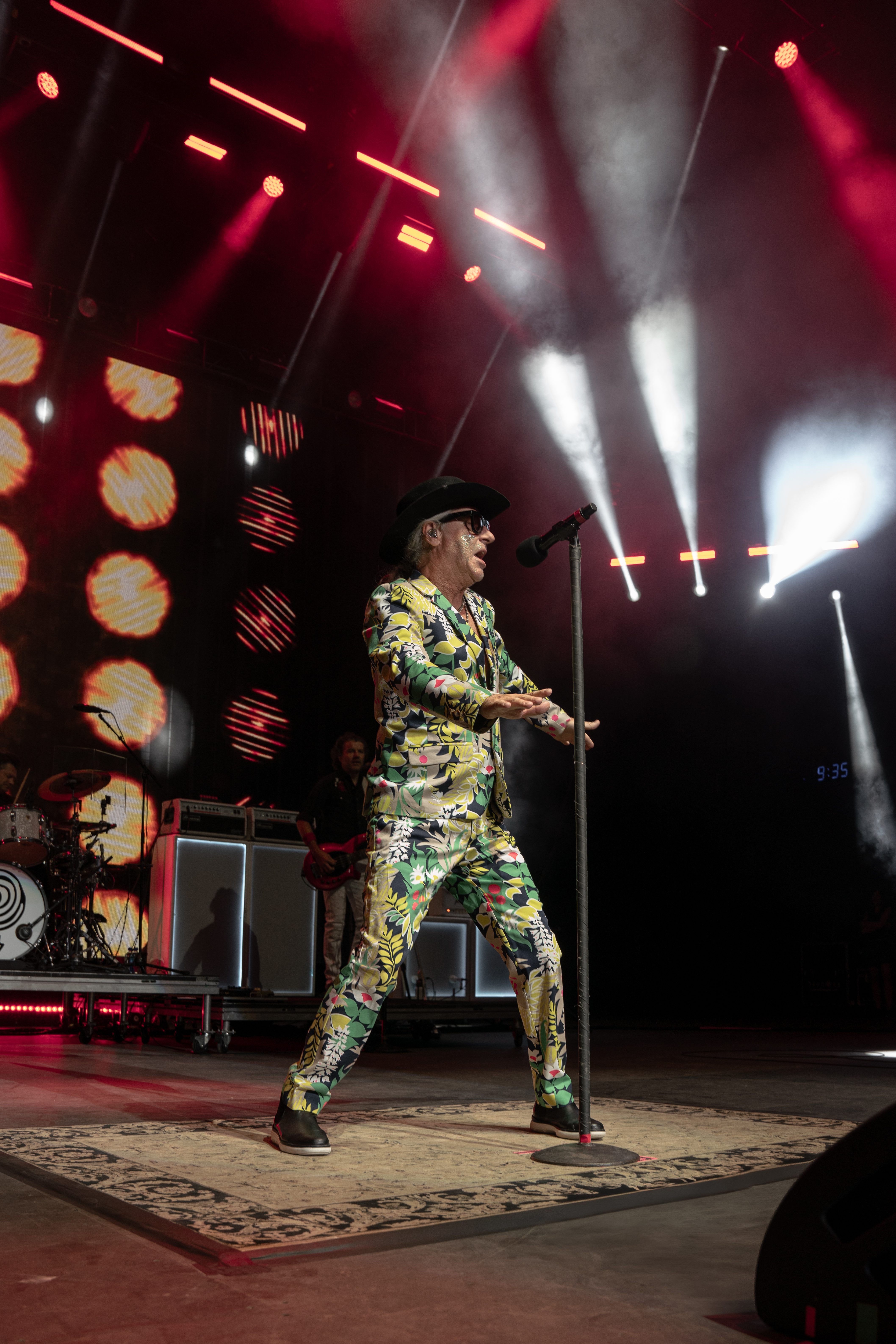 Lead singer of Collective Soul performing on stage in a vibrant patterned suit with dramatic lighting effects.