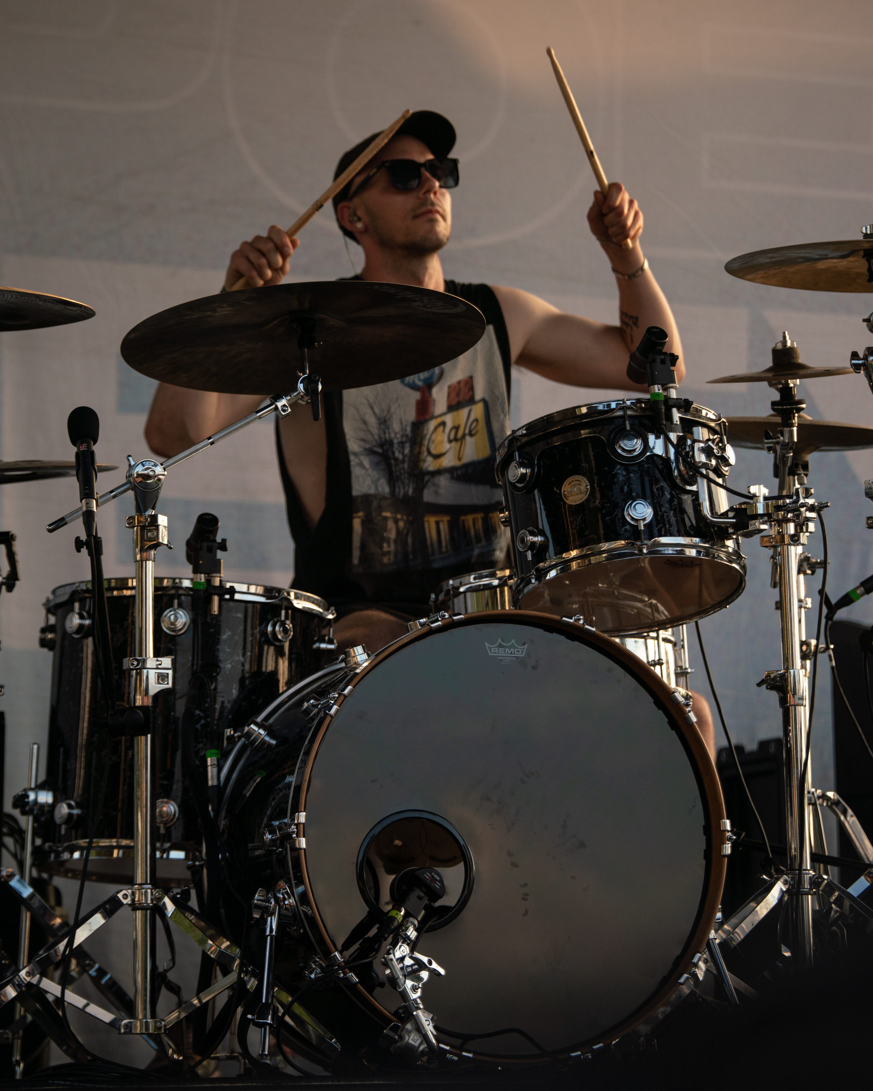 A drummer performing on stage during a music festival, holding drumsticks and playing with intense focus.