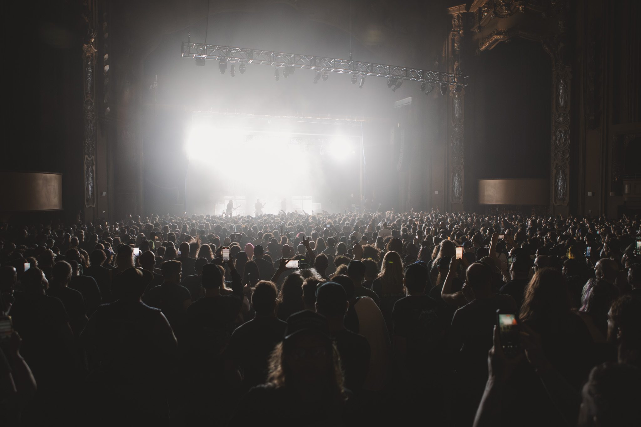 A crowded concert scene at the Brooklyn Paramount, with fans gathering in anticipation of Acid Bath's performance, illuminated by bright stage lights.