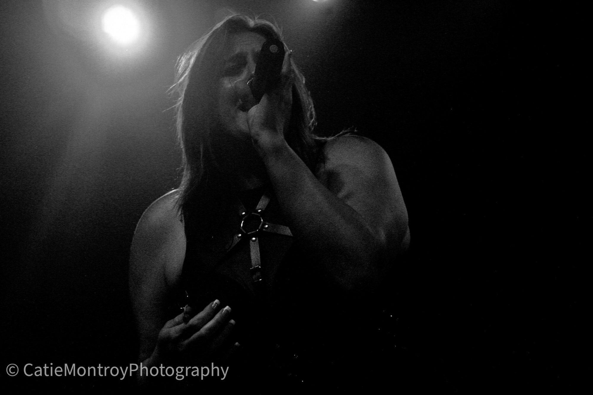 Lead singer performing passionately on stage with a microphone, captured in a dramatic black and white setting.