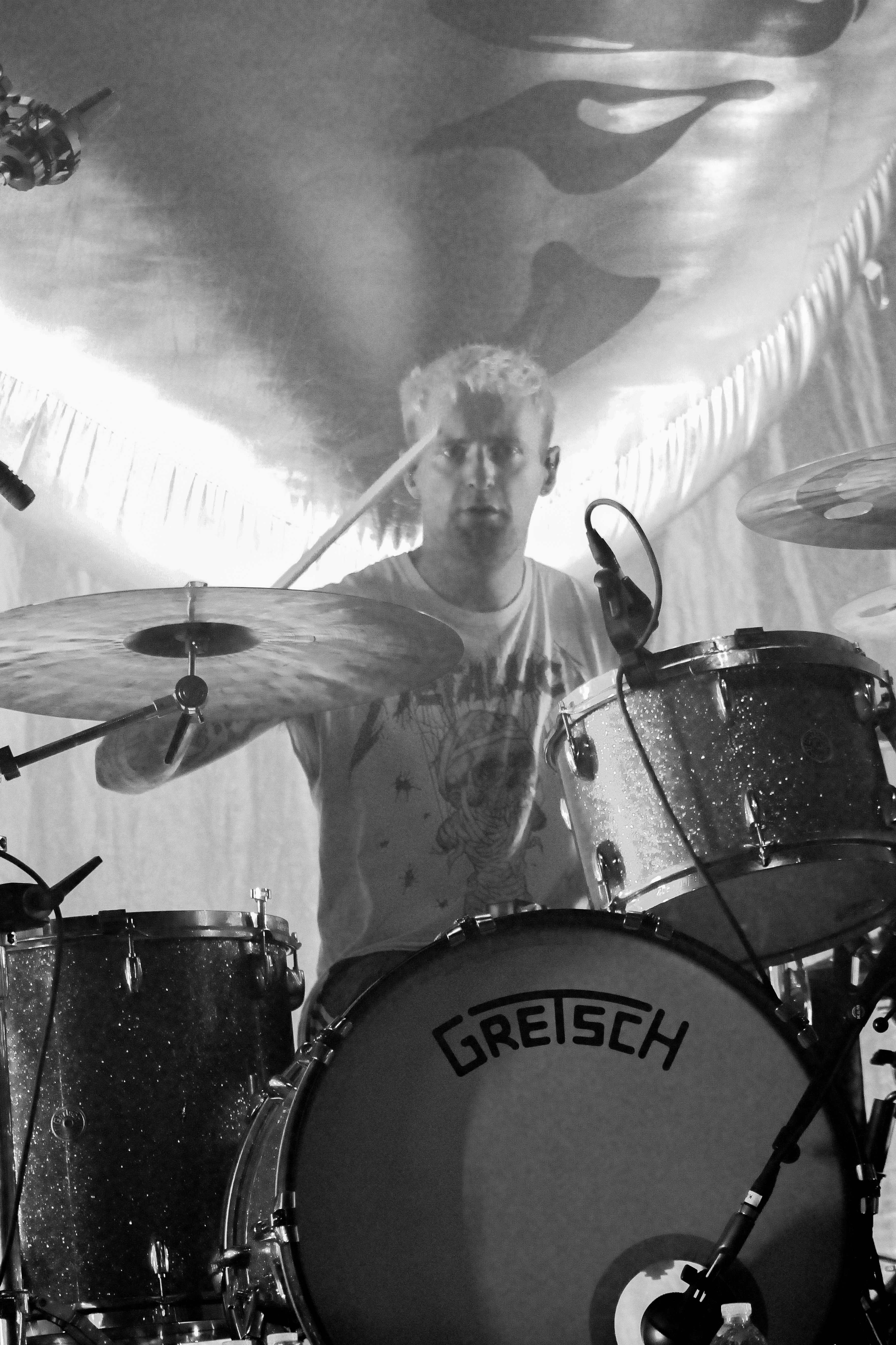 Drummer of Fontaines D.C. performing live on stage, wearing a Metallica t-shirt and focused on playing.
