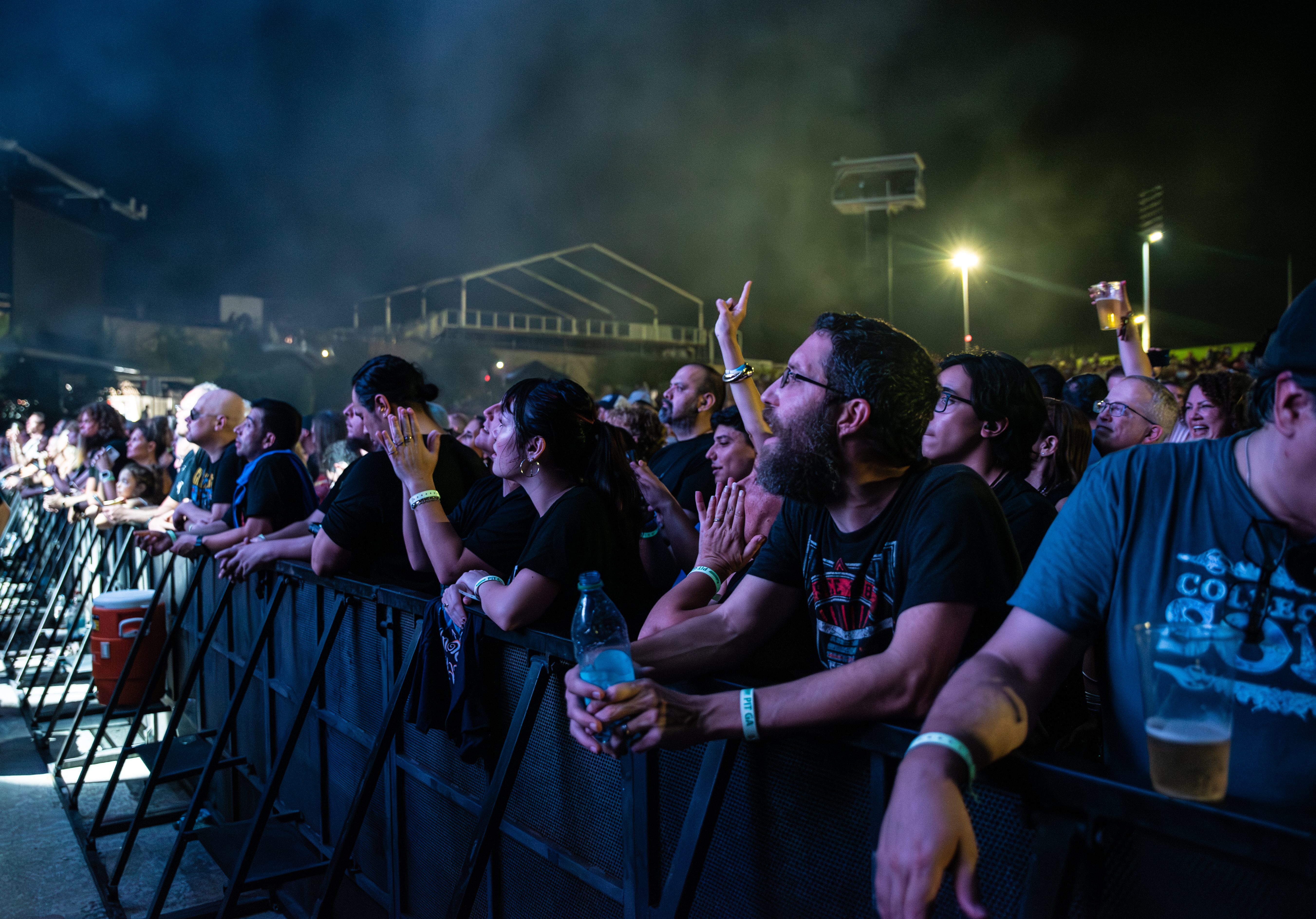 A diverse crowd of concertgoers engages enthusiastically at a live music event, with people cheering, clapping, and enjoying the performance.