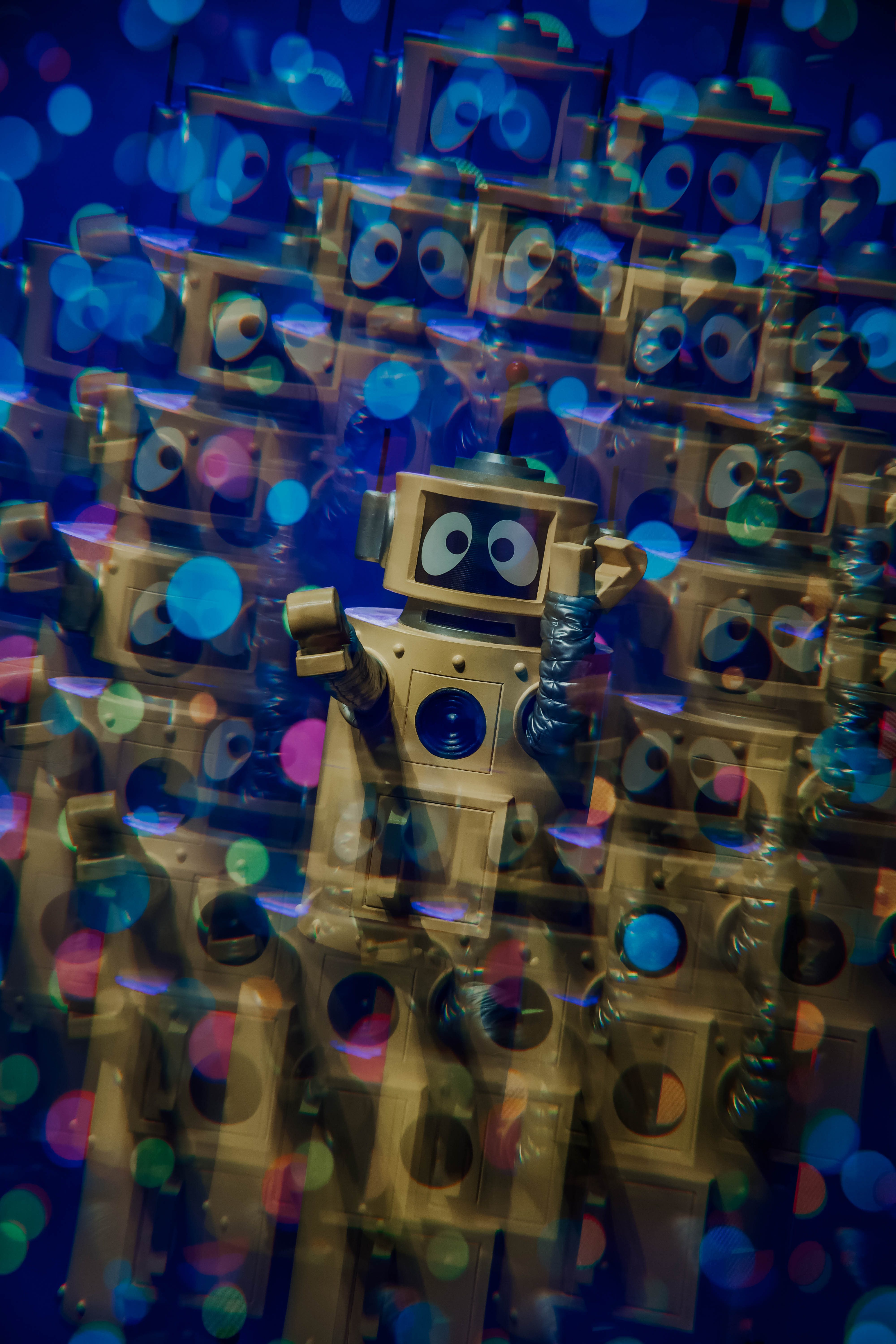 A whimsical scene featuring a group of colorful robot toys, with large eyes, set against a vibrant, blurred background of multicolored bokeh lights.