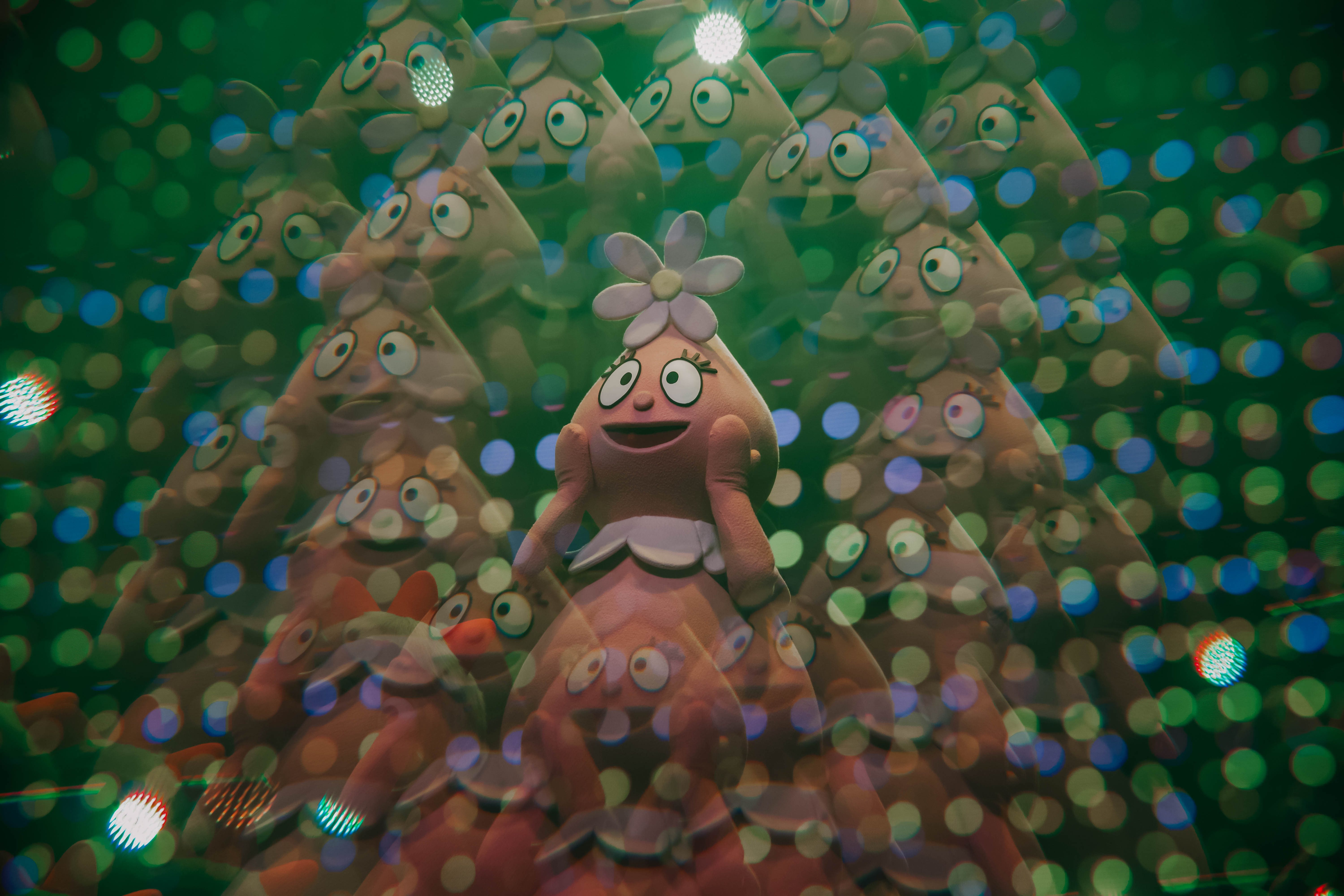 A vibrant stage scene featuring a character from Yo Gabba Gabba! surrounded by colorful lights and confetti.