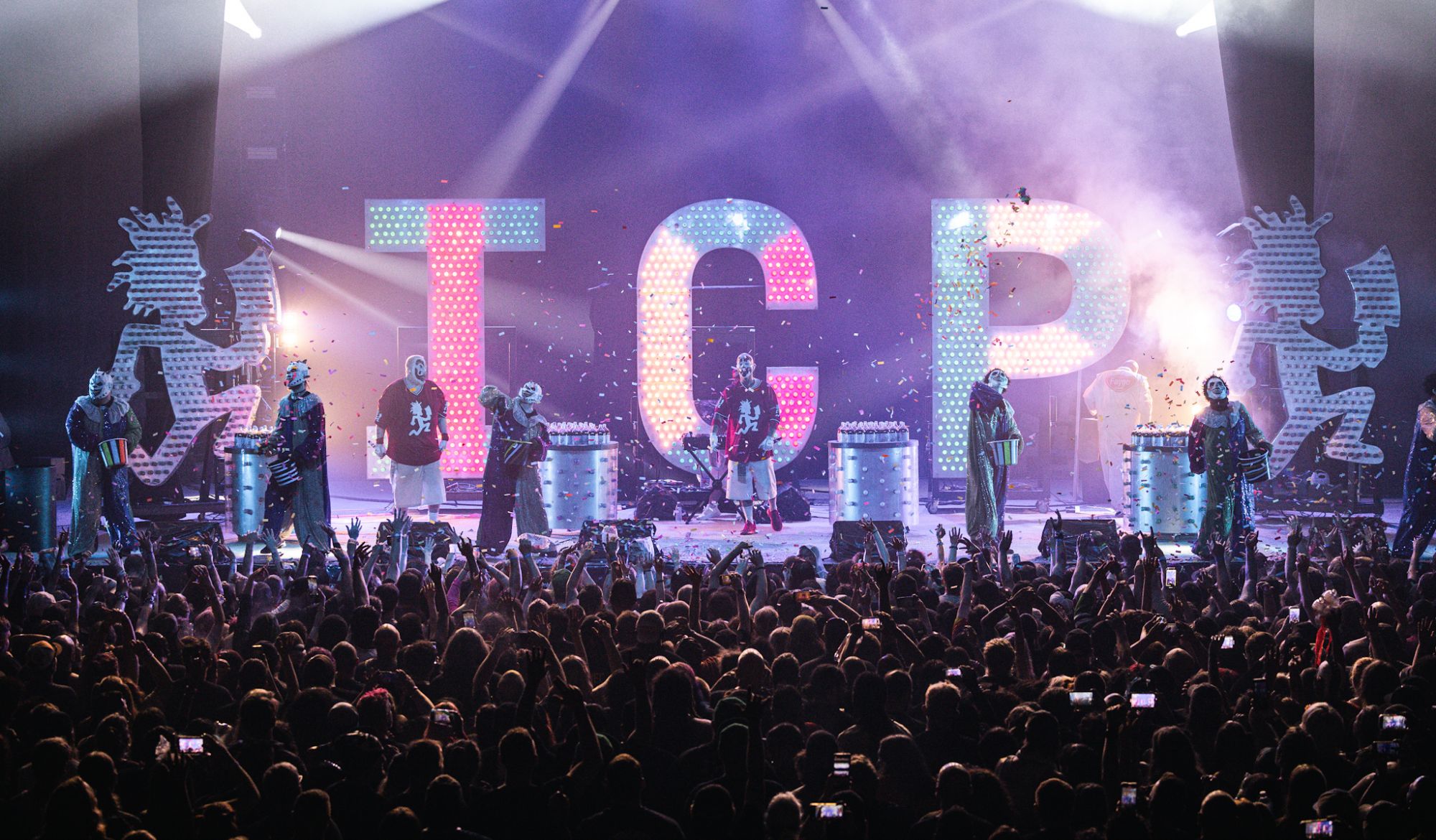 Insane Clown Posse performing live on stage with large illuminated letters 'ICP' in the background, surrounded by an enthusiastic crowd.