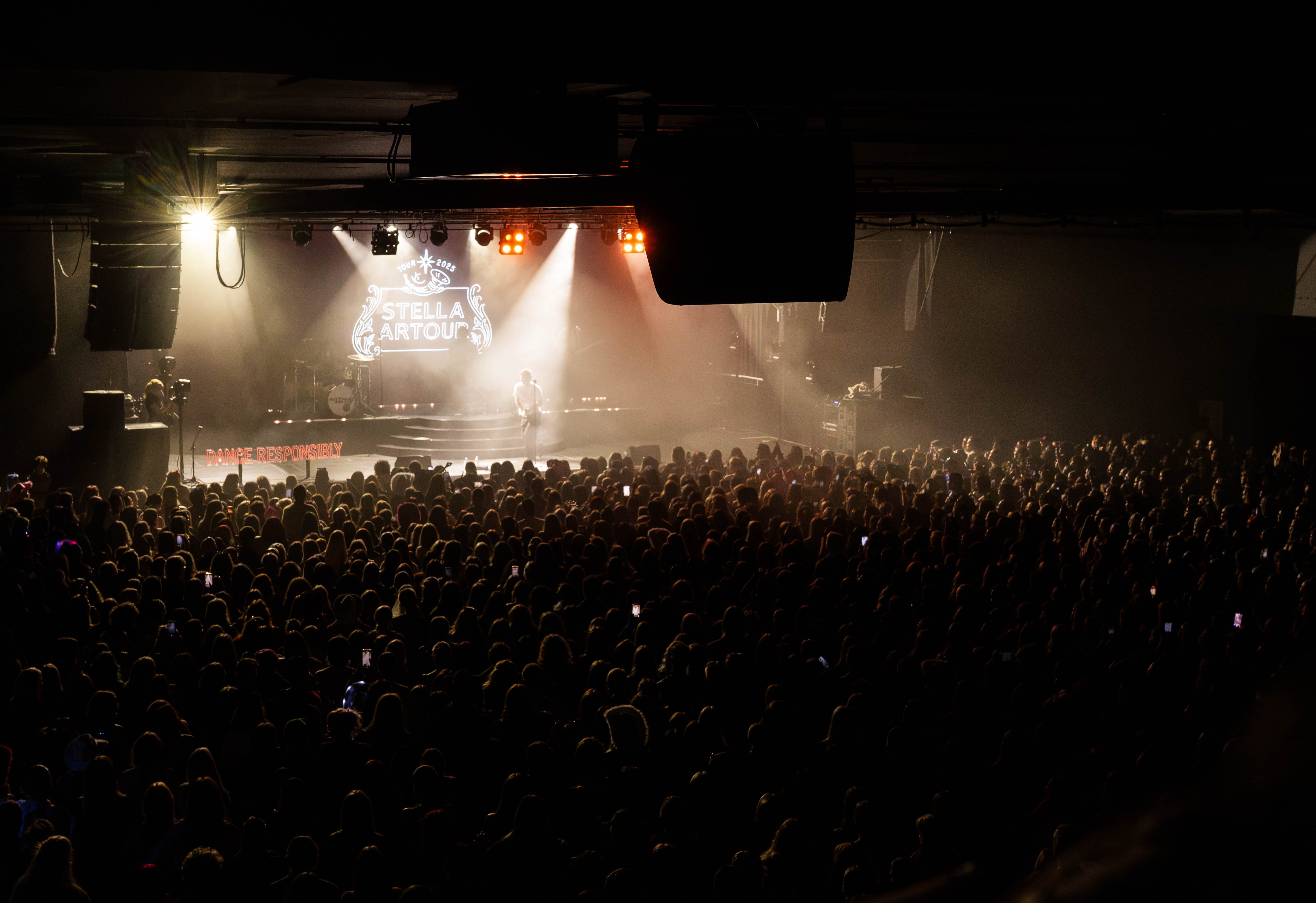 A live performance by Arthur Hill at Manchester Academy, with a large crowd of fans enjoying the show under stage lights.