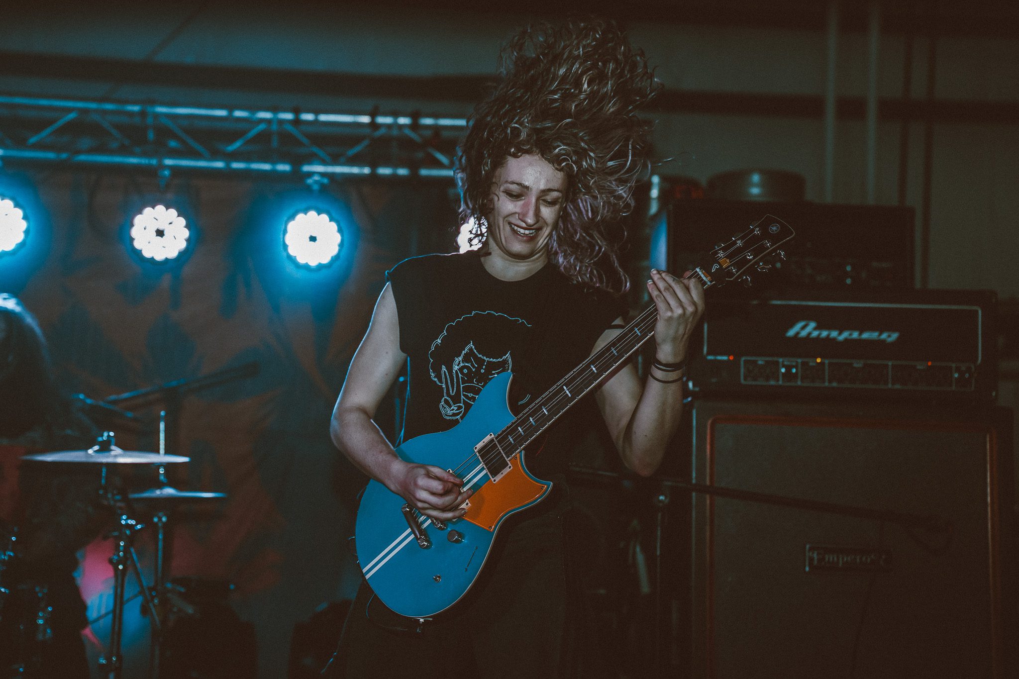 Scenic view of a beach with golden sand and rocky cliffs under a clear blue sky, featuring gentle waves and people walking leisurely along the water's edge.